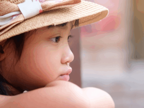 Enfant pensif portant un chapeau, le regard tourné vers l’extérieur, illustrant le stress et l’anxiété que peuvent vivre certains enfants.