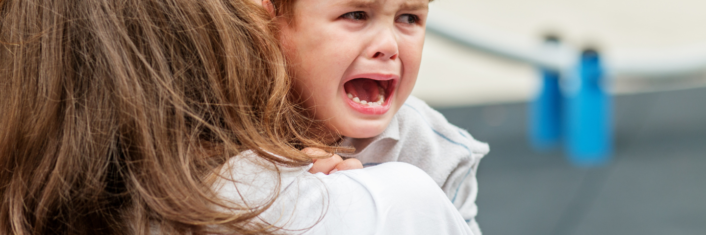 Jeune enfant en pleurs, réconforté par un adulte, illustrant les émotions et l’anxiété que certains enfants peuvent vivre à l’approche de la rentrée scolaire.