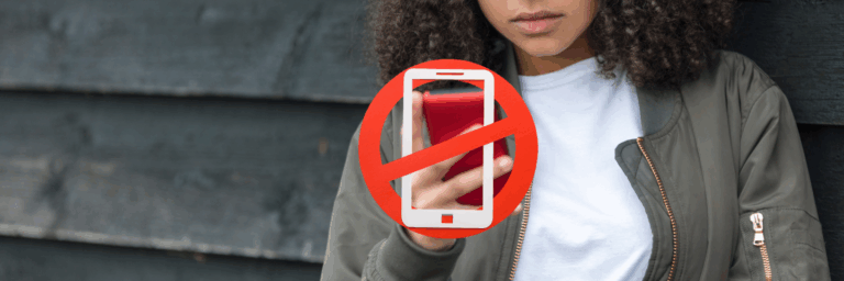 « Une adolescente regarde un téléphone rouge, partiellement caché par un grand symbole d’interdiction de cellulaire, indiquant l’interdiction d’utiliser les téléphones dans les milieux scolaires.