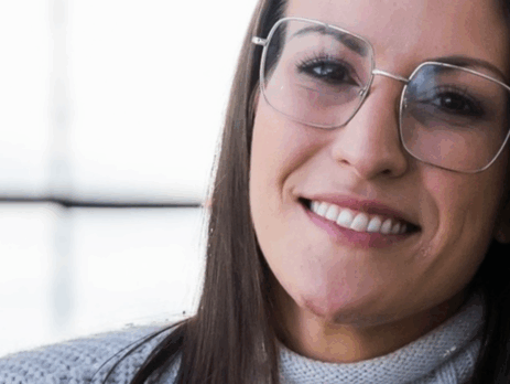 Portrait de Caroline Quarré, intervenante psychosociale, souriante, portant des lunettes, dans un environnement lumineux.