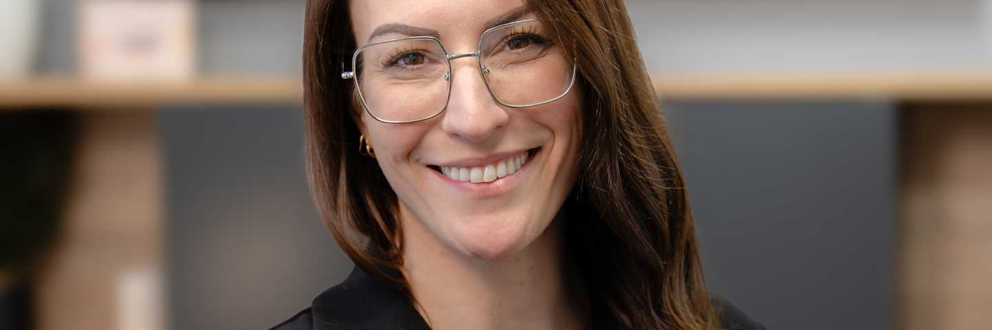 Portrait de Caroline Quarré, intervenante psychosociale et autrice, souriante, portant des lunettes, dans un environnement professionnel.